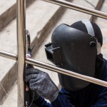 Welder working a welding metal with protective mask and sparks.